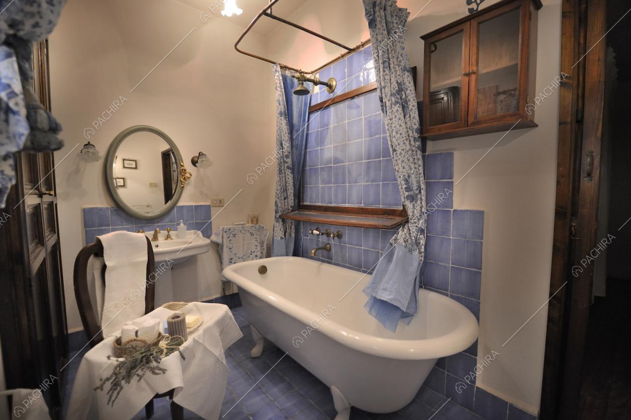 Vasca da bagno, piastrelle azzurre e specchio tondo con cornice
