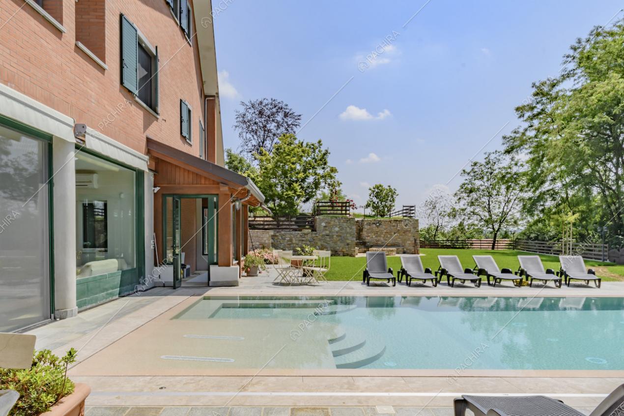 Piscina a sfioro della location, con lettini a bordo vasca e veranda dalle ampie vetrate