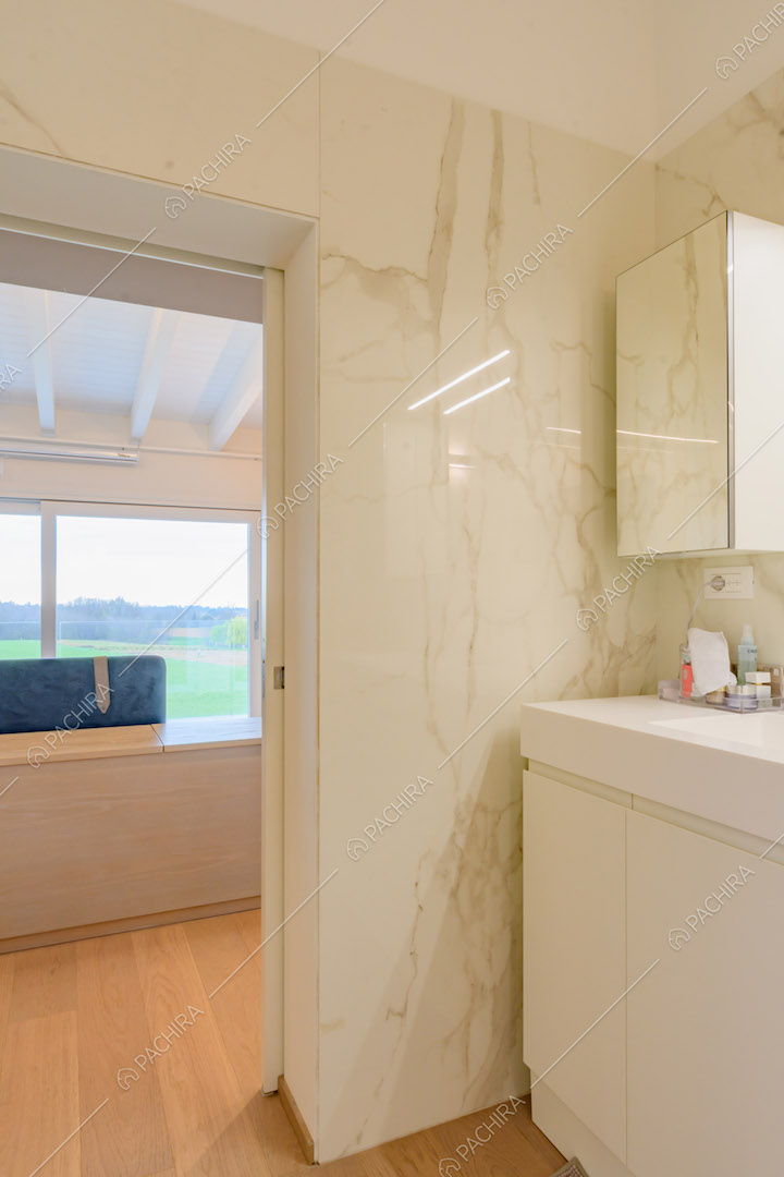 Bagno della camera da letto con pareti in marmo bianco e pavimento in parquet