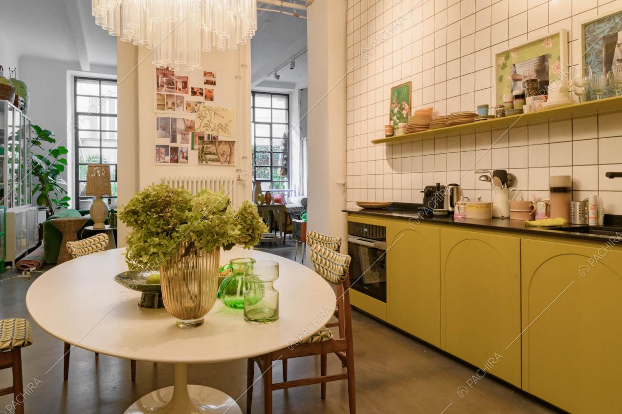 Cucina color senape a parete con vista sulla zona living e con lampadario di design