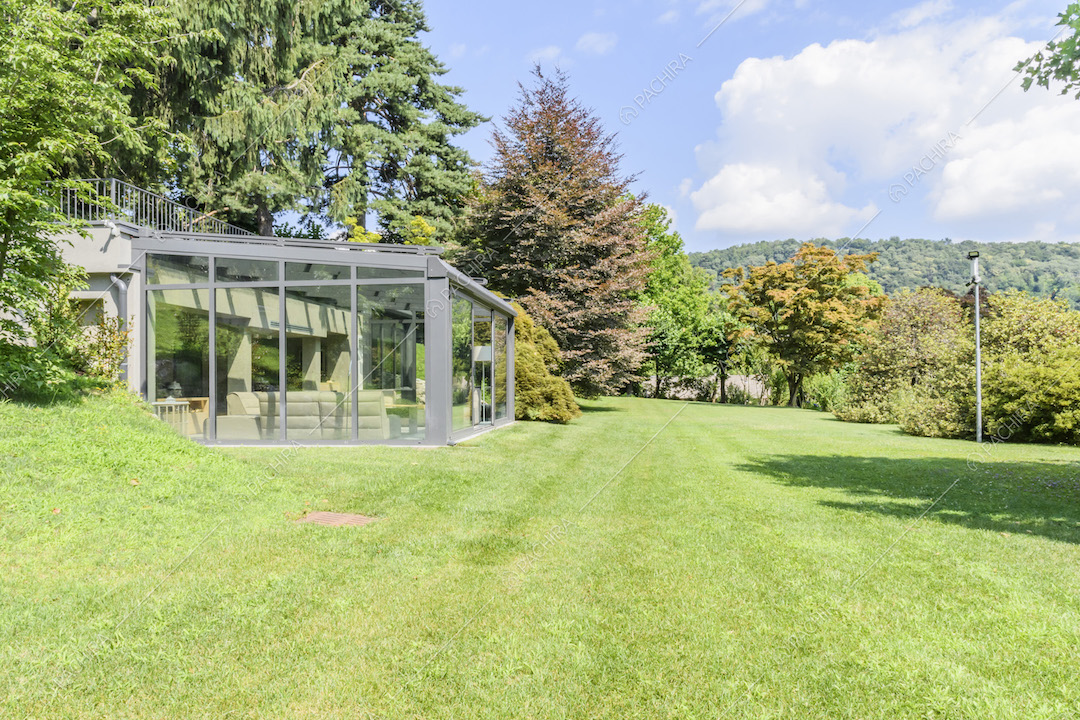 Giardino con serra arredata e alberi di diverse specie
