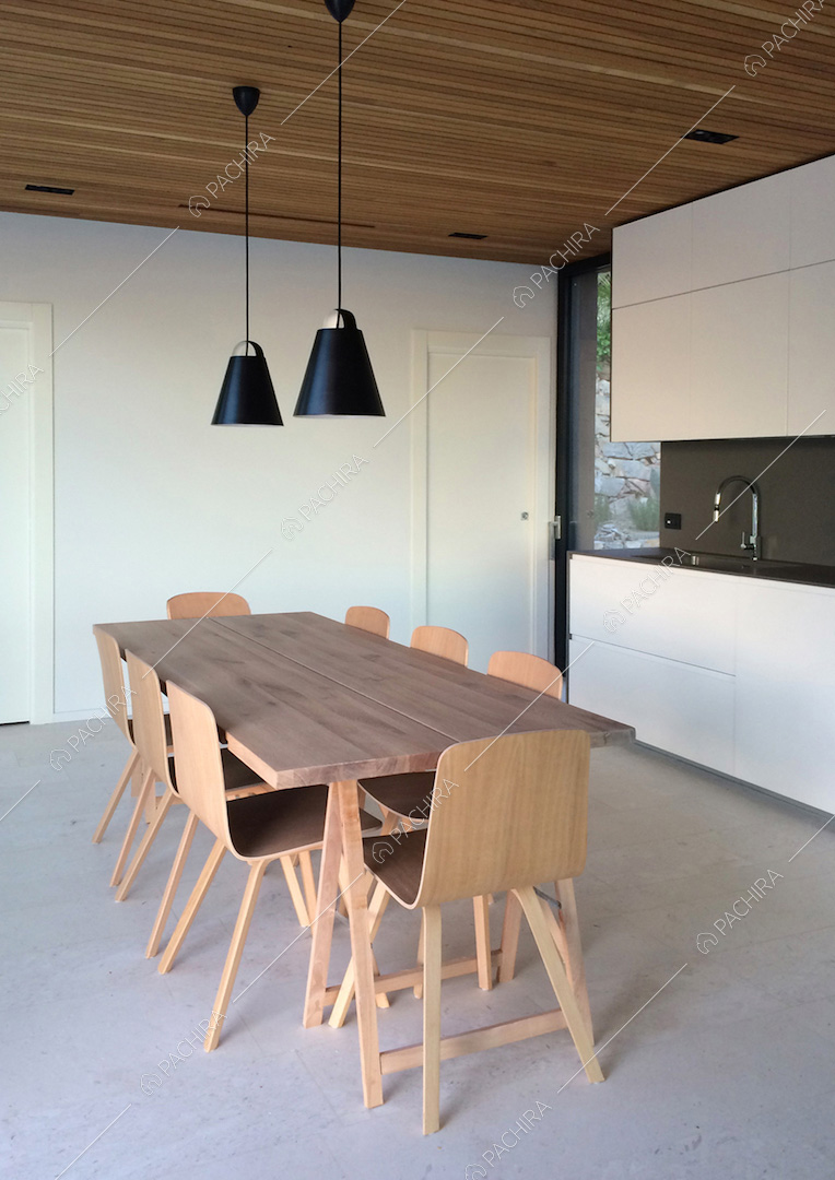 Tavolo da pranzo in legno nella cucina dalle pareti bianche con fornelli a induzione