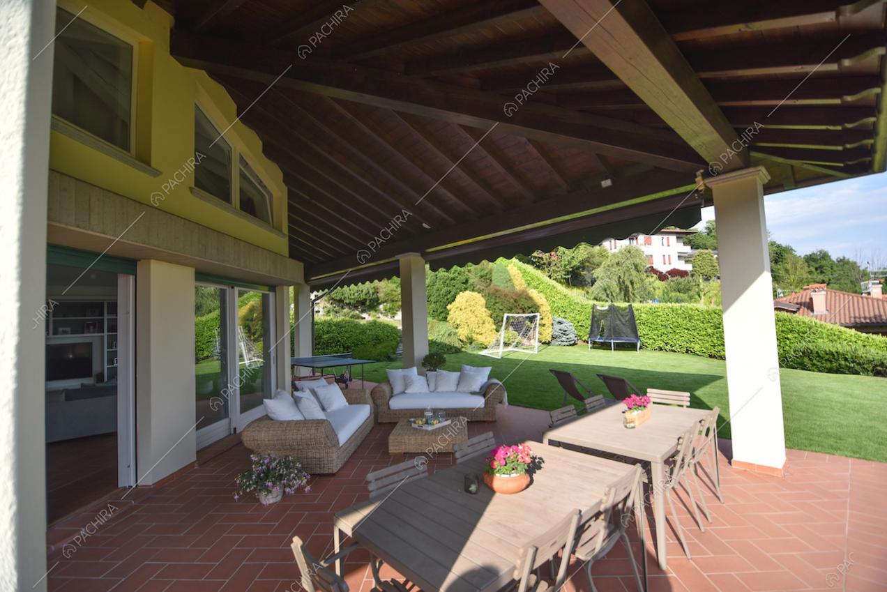 Veranda con travi a vista, tavoli con sedie e divani da esterno