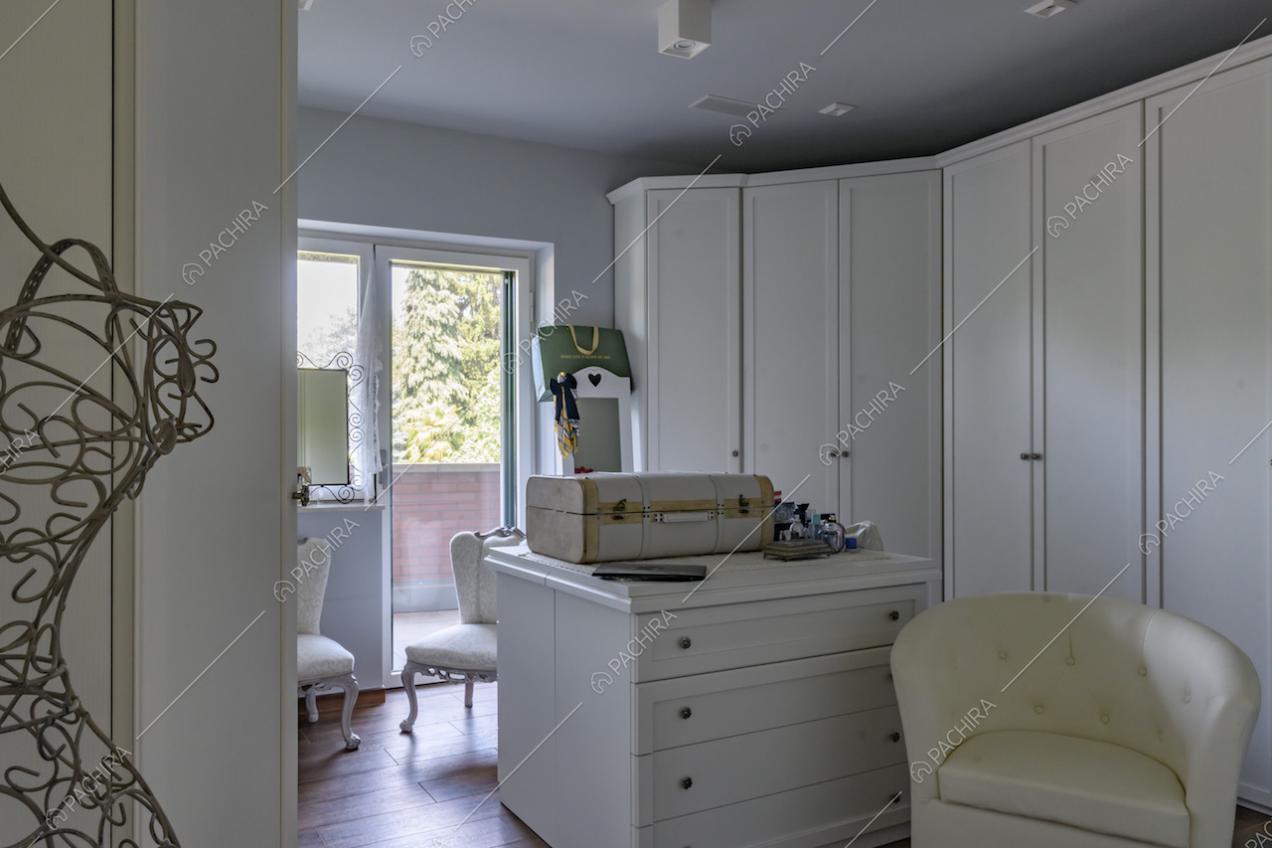 Ampia cabina armadio con pavimento in parquet e porta-finestra per accedere al balcone