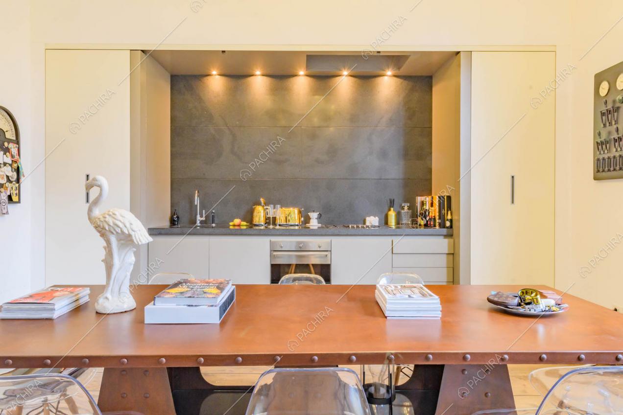 Tavolo da pranzo nella cucina con pavimento in parquet e parete grigia