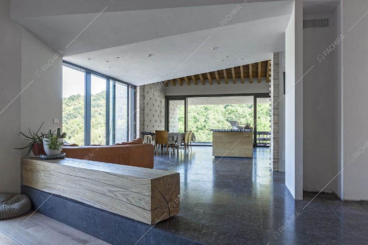 Pavimento nero in marmo nella sala con grandi vetrate e soffitto in travi in legno