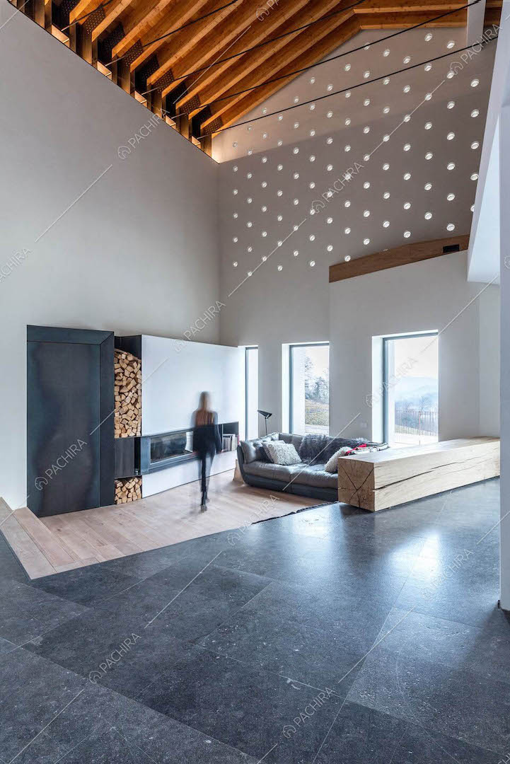 Open space con pavimento in marmo nero e in parquet, camino e alto soffitto