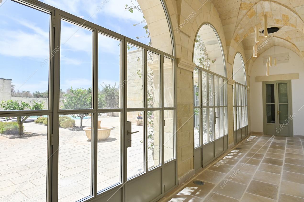 Dal corridoio, tramite le porte-finestre in stile industriale, vista sul cortile