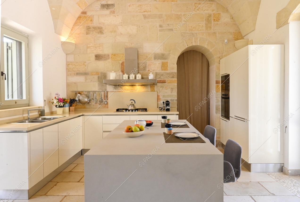 Luminosa cucina con fornelli a gas, isola con bancone e sgabelli e soffitto ad arco