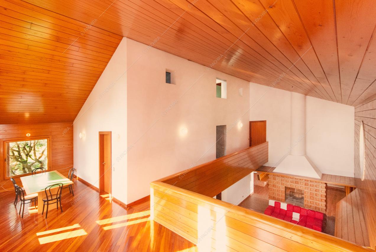 Soffitto rivestito in legno e vista sulla zona giorno con camino