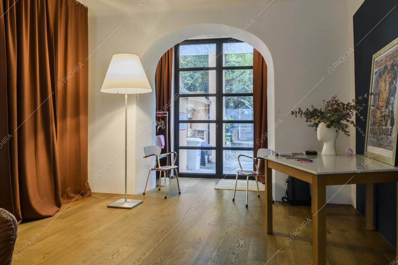 Studio con pavimento in parquet, pareti bianche e arco che apre la visuale sul giardino