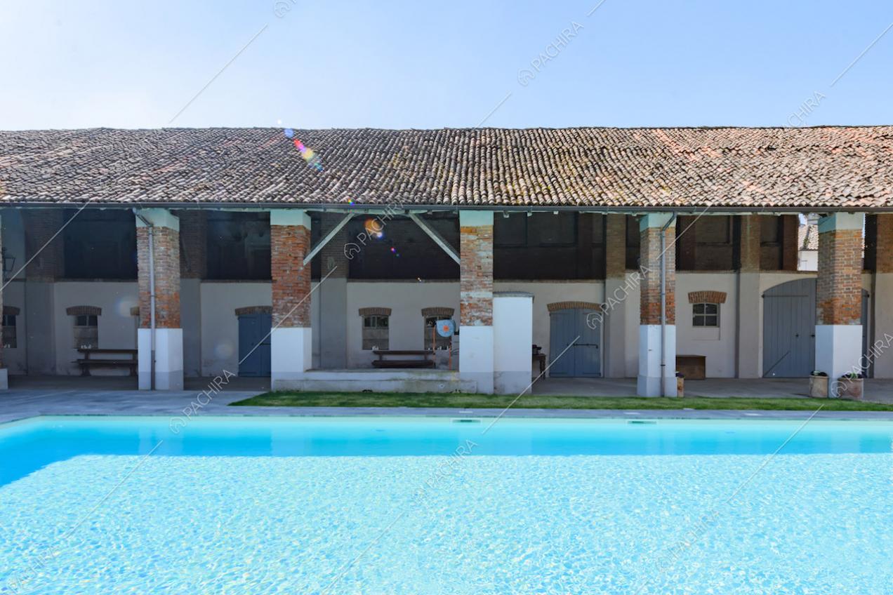 Piscina con vista sul portico con colonne in mattoni a vista dell'ex fienile