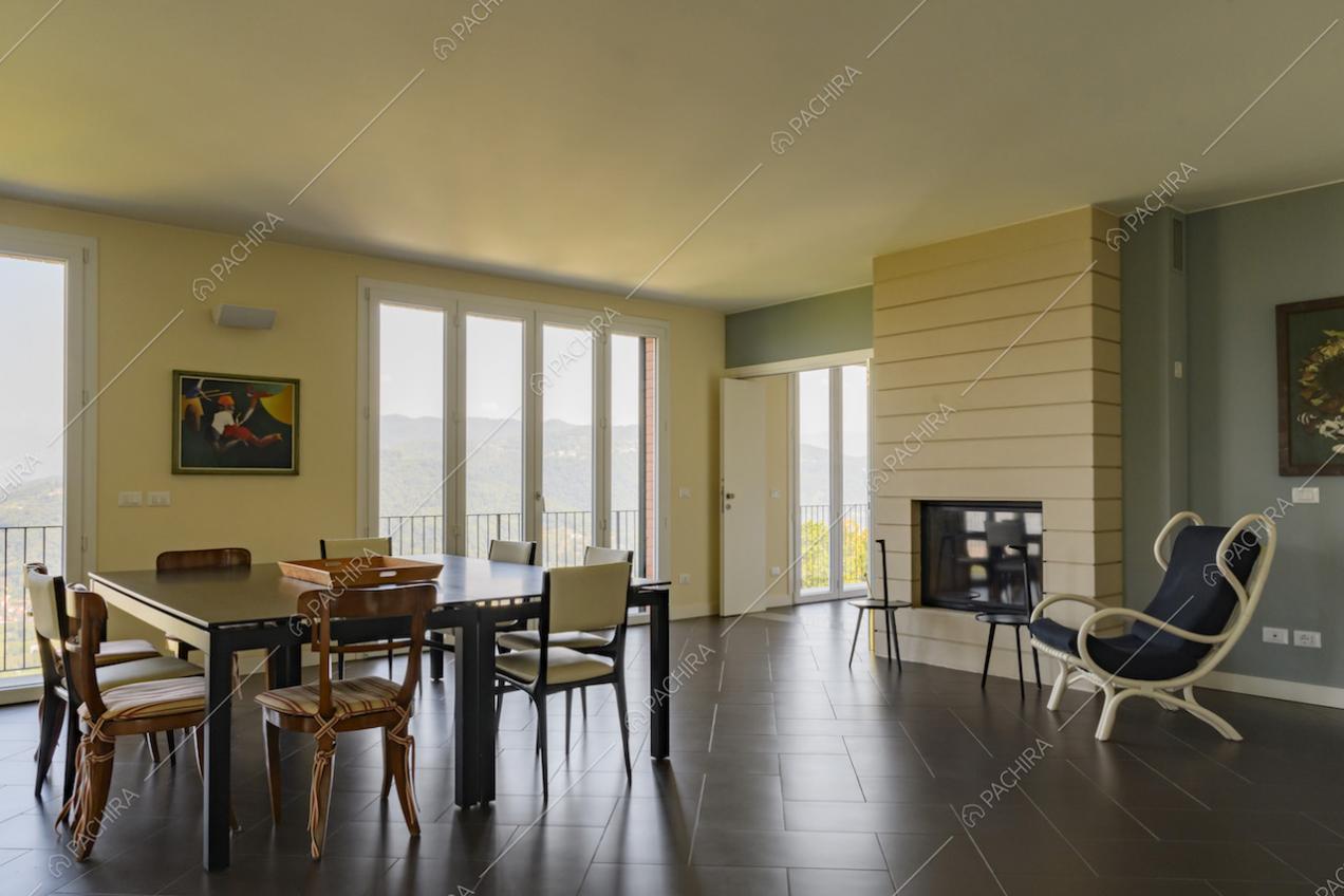 Sala da pranzo con camino, collegata a un'altra sala e con ampie vetrate