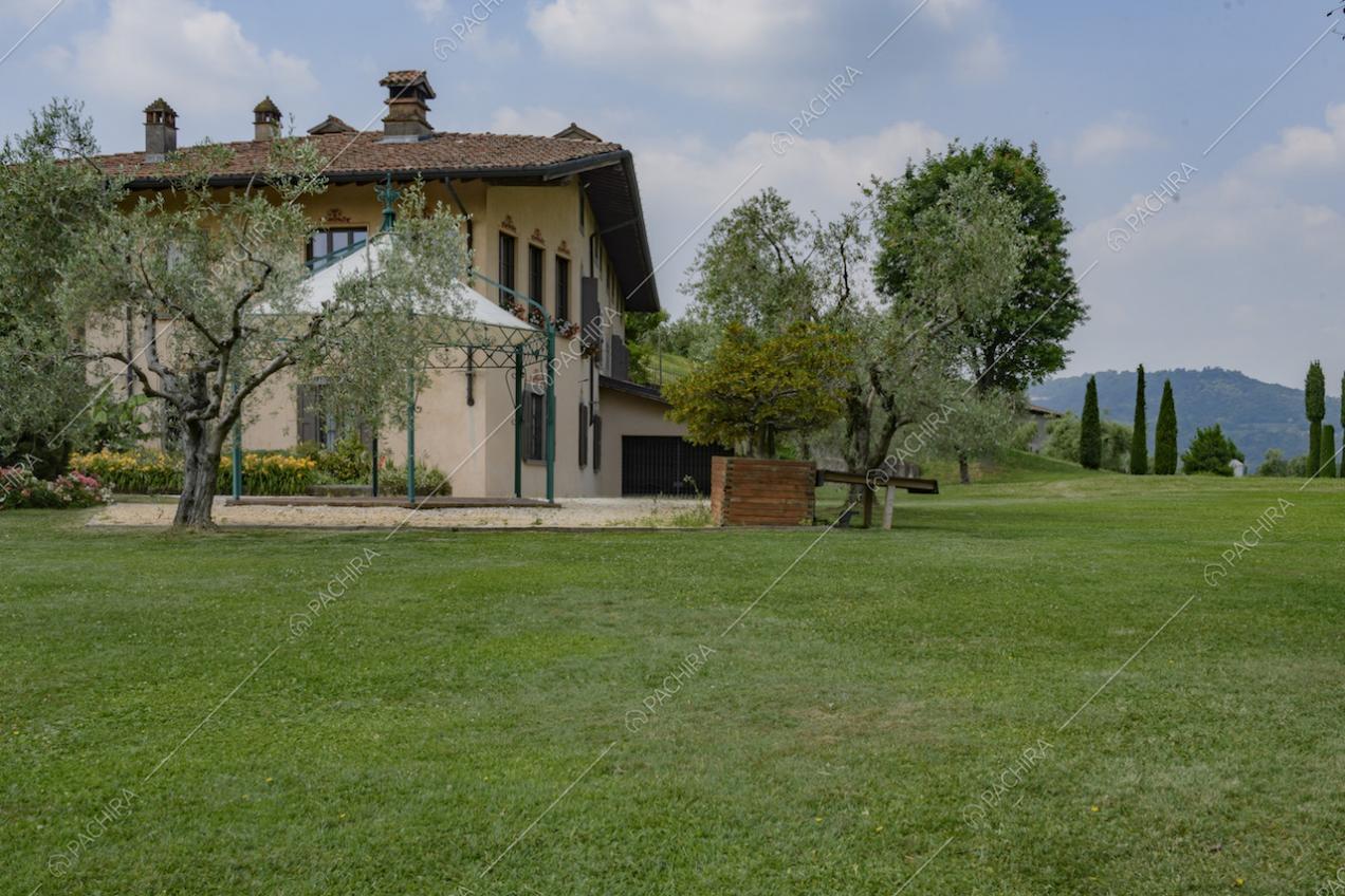 Dettaglio esterno della villa con alberi e prato