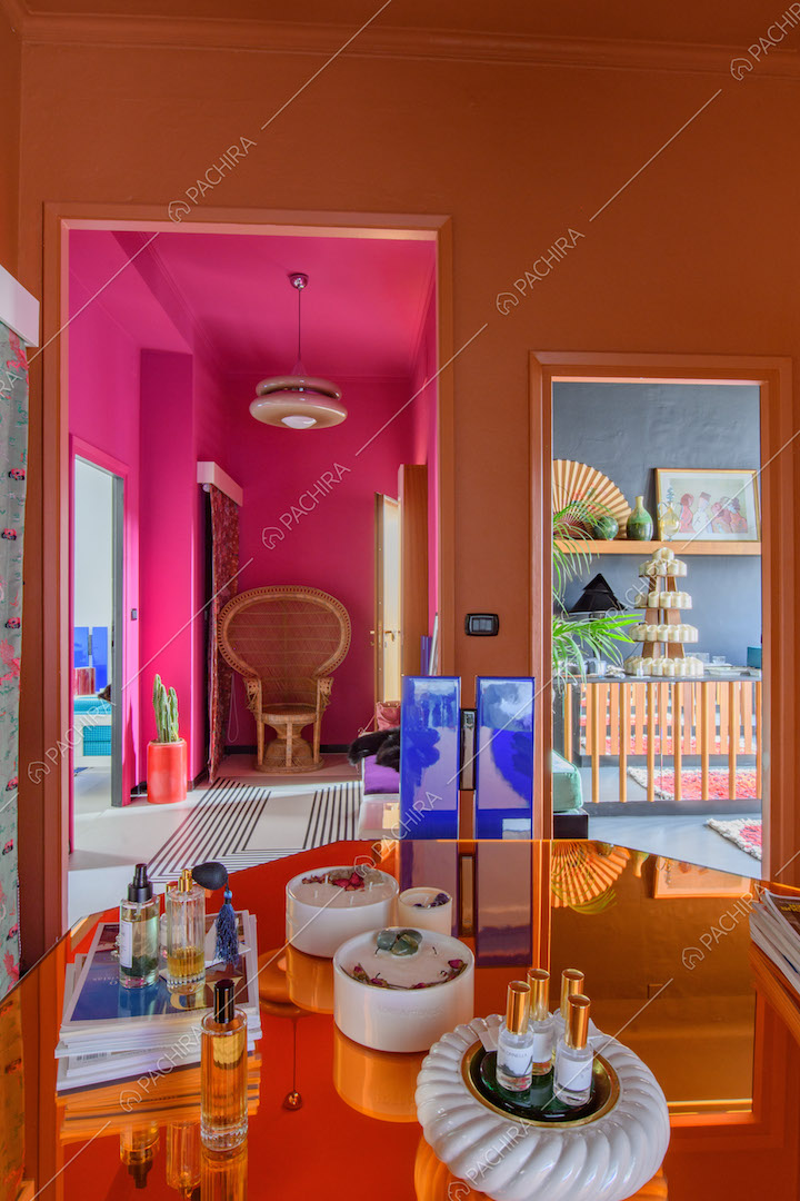 Tavolo arancione a specchio con vista sul corridoio fucsia con poltrona e sulla cucina