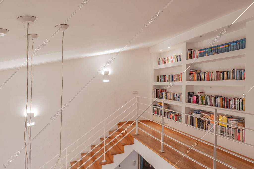 Libreria sul soppalco con ringhiera bianca della villa Bauxite, location in stile moderno a Roma