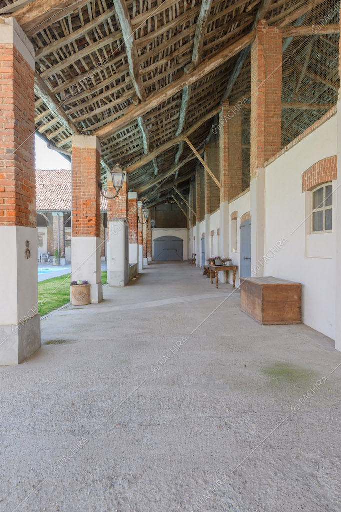 Grande porticolo con soffitto in legno e colonne bianche e in mattoni rossi a vista