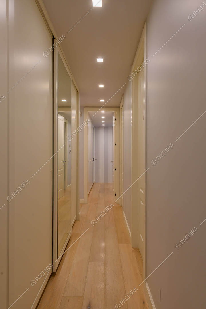 Luminoso corridoio con pavimento in parquet e porte bianche