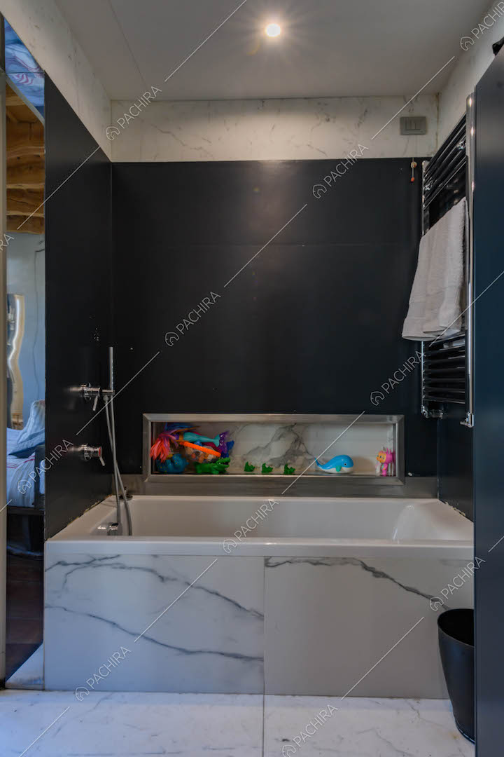 Bagno con pareti nere e vasca in marmo