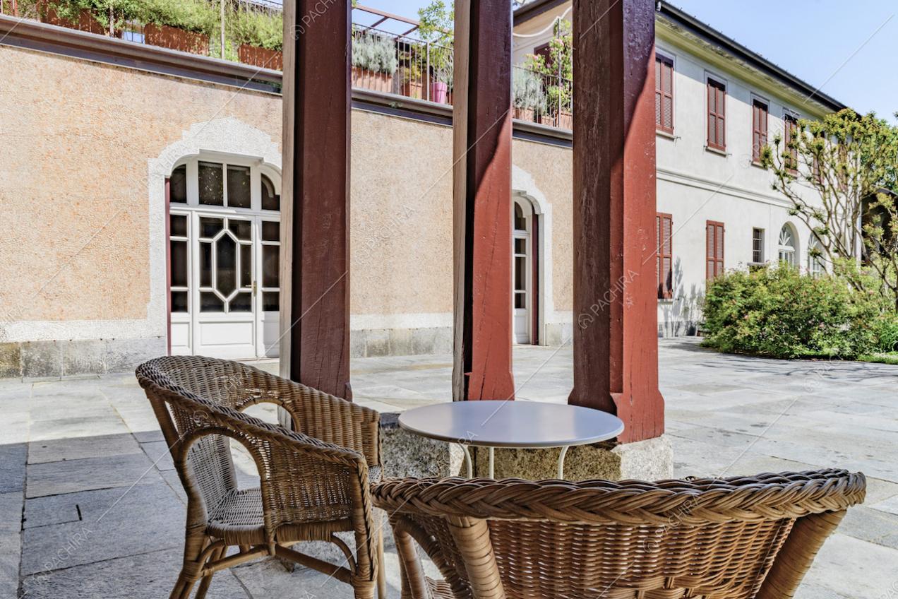 Nel cortile d'ingresso salottino da esterno con colonne rosse e vista sulla terrazza del primo piano