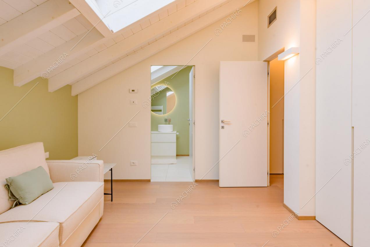 Sala con divano bianco, pavimento in parquet e soffitto con lucernario