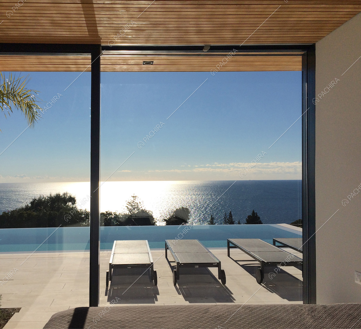 Dalla camera da letto matirmoniale, vista sulla terrazza con lettini e piscina a sfioro, e sul mare