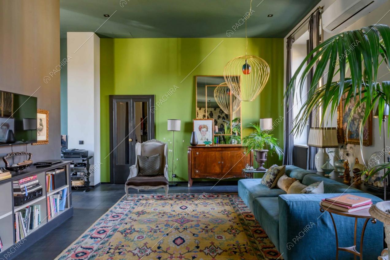 Sala con divano in velluto azzurro, ampio tappeto e pavimento nero in gres 