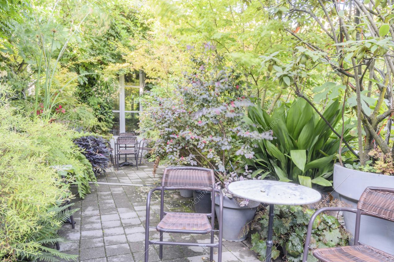Tavolino tondo in marmo e sedie immersi tra le piante del giardino